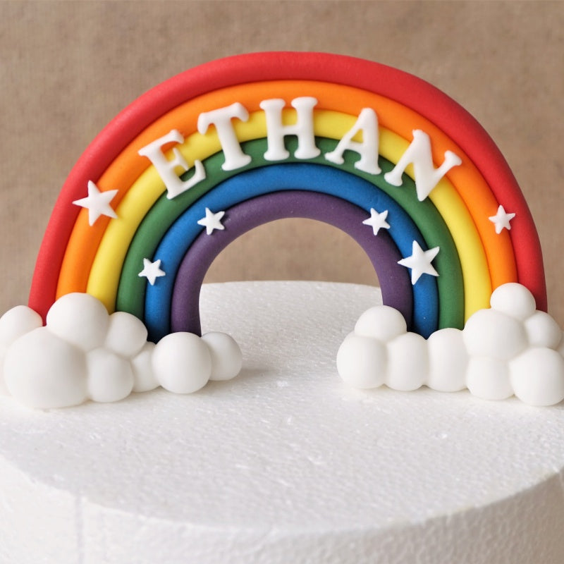 Bold fondant rainbow cake topper with clouds and name